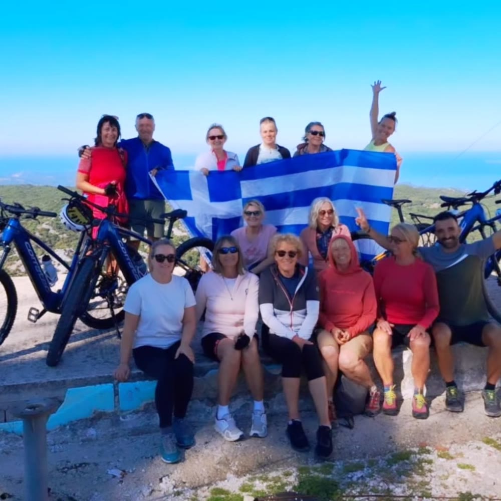 Gruppe mit E-Bikes hält eine griechische Flagge